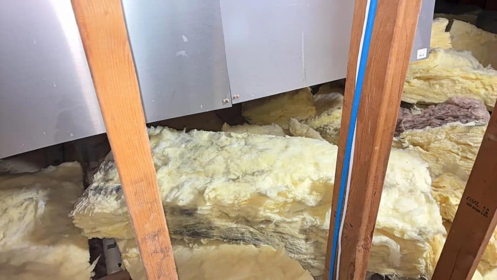 Insulation and wood beam detail in attic corner during mold remediation in Scarsdale, NY