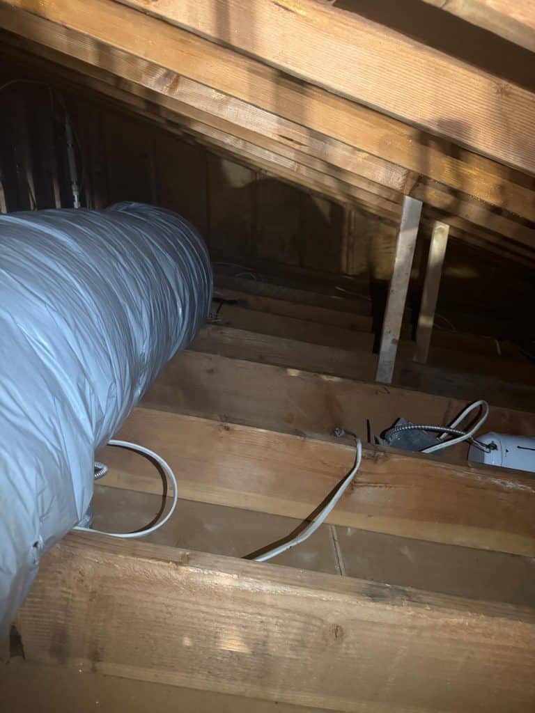 Flexible ductwork running along attic floor joists during remediation work in Scarsdale, NY