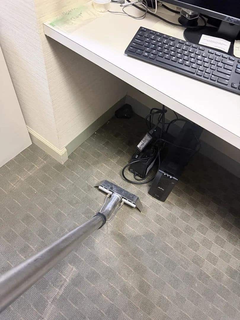 Technician extracting water from carpet under a reception desk at an Armonk dental office