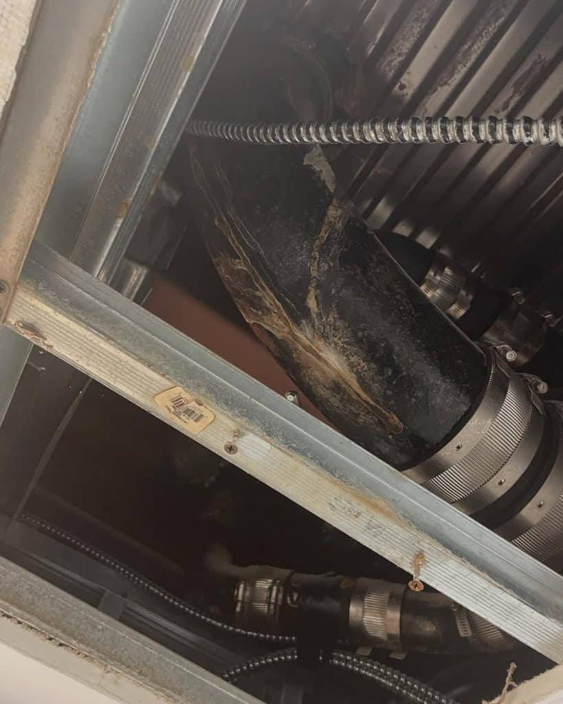 Corroded pipe and ductwork exposed in a ceiling during post-storm surge system inspection