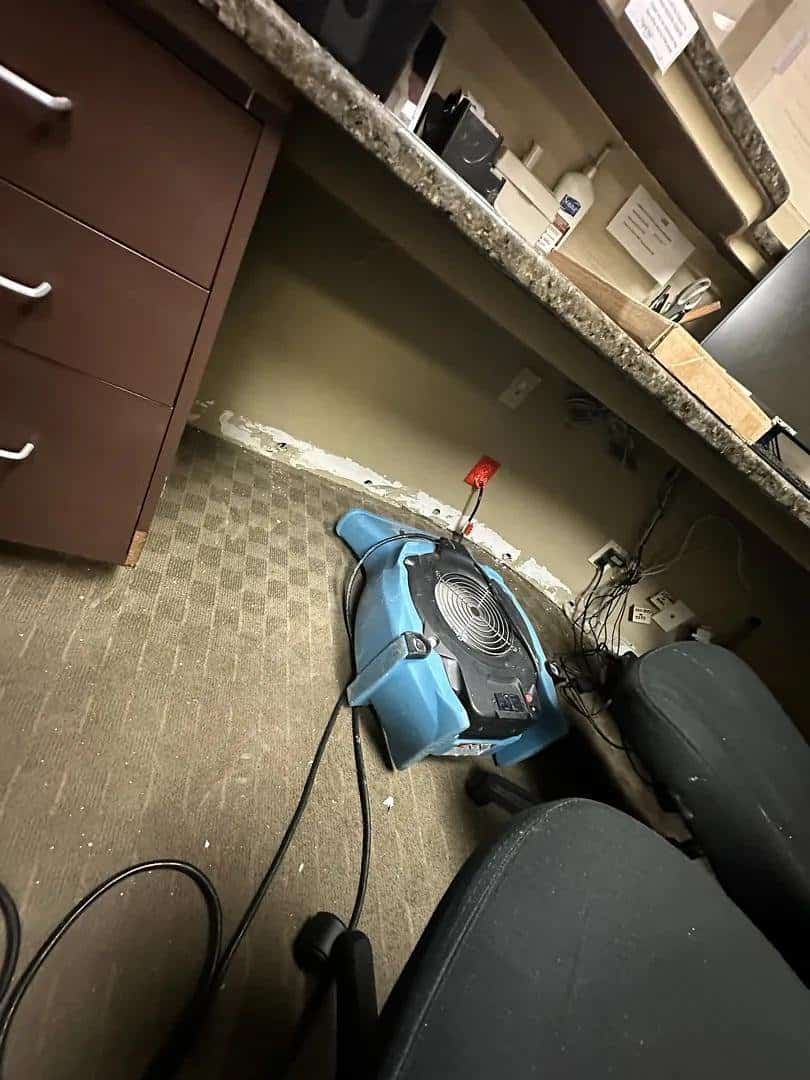 Air mover drying the wall cavity under a dental office reception counter in Armonk, NY