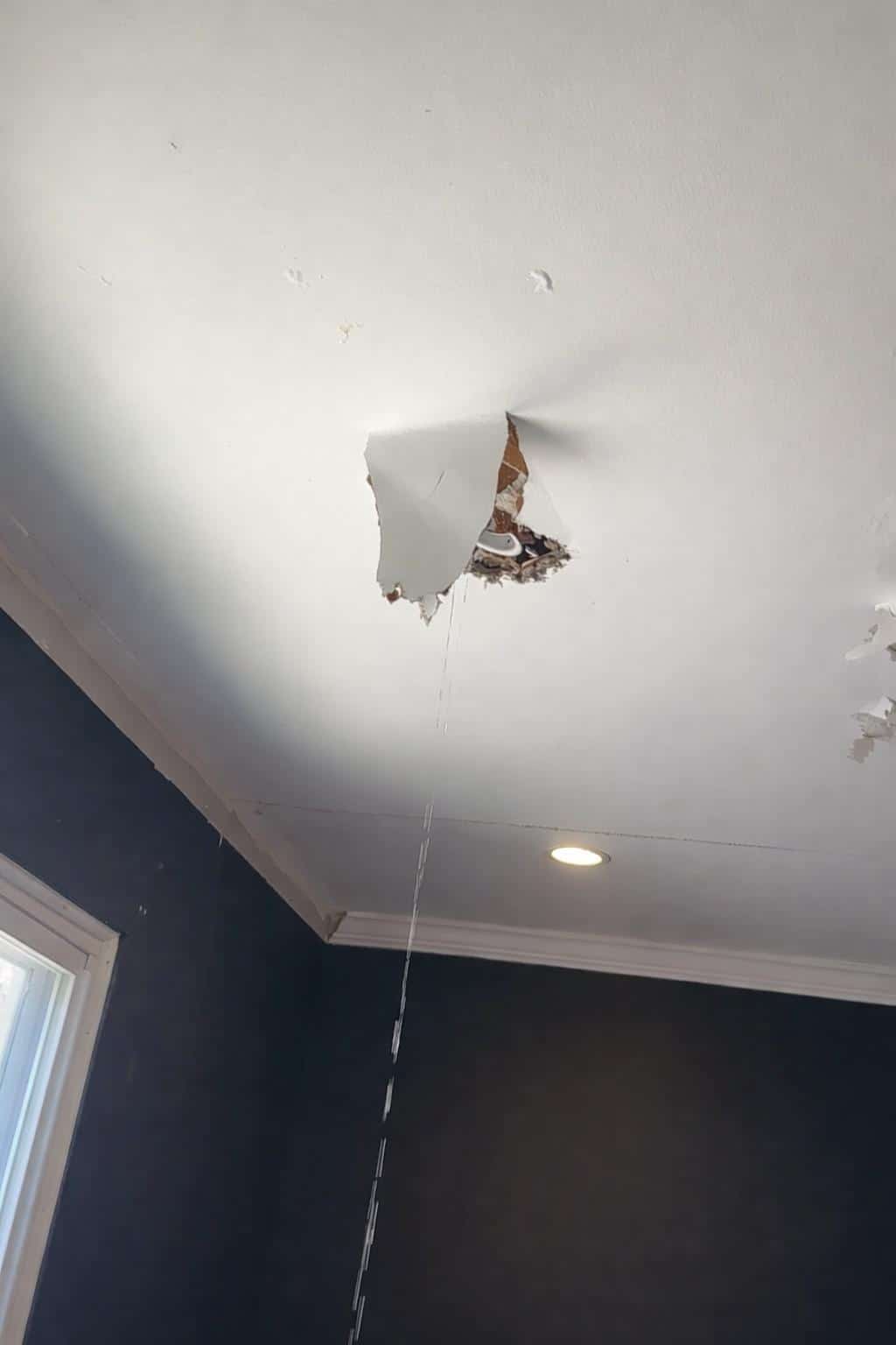 Ceiling leak and torn drywall from ice dam water damage inside a home