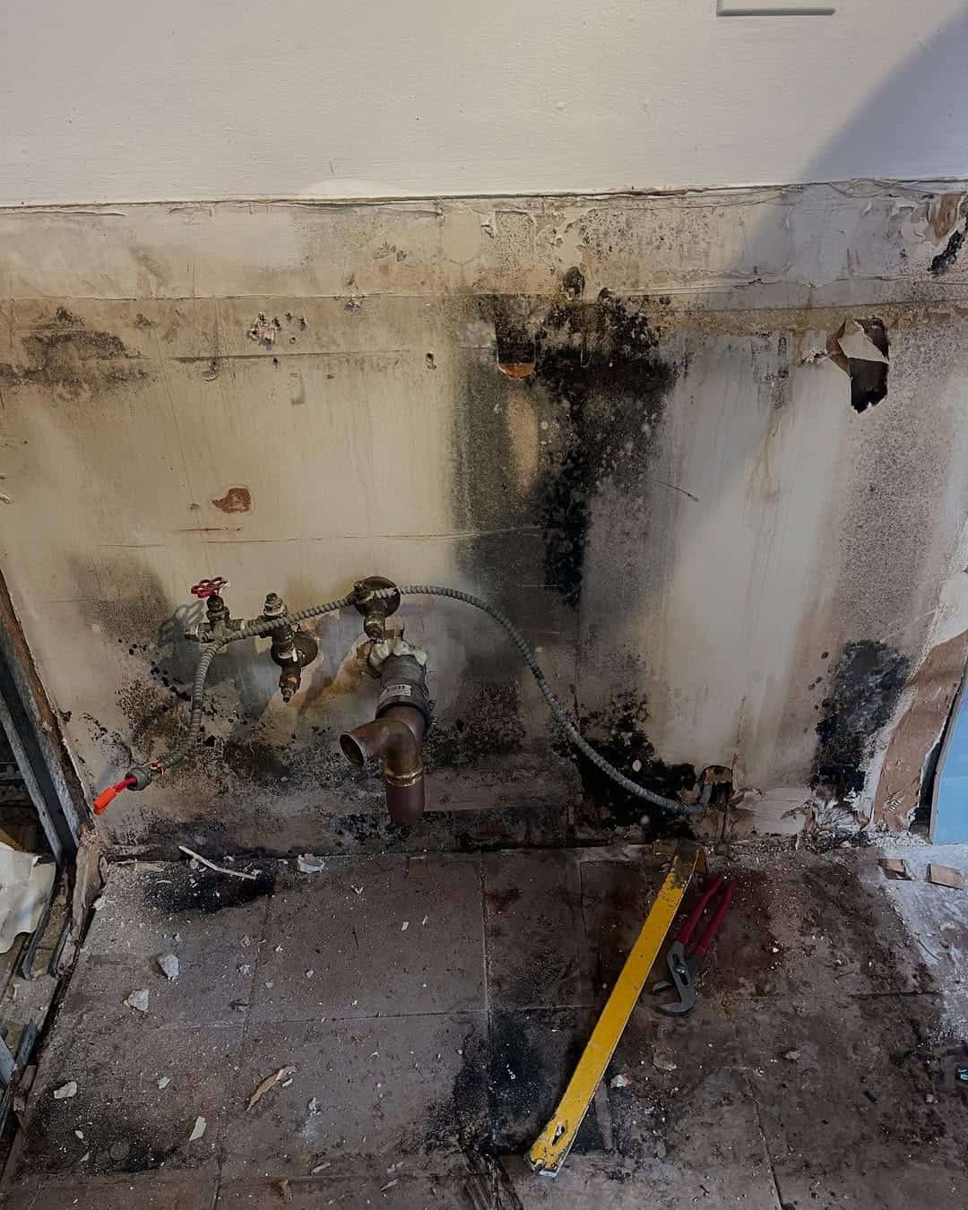 Water-damaged wall and exposed plumbing in a basement after an urban flood